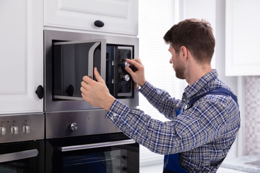 A man in an apron works on a microwave oven, highlighting kitchen appliance repair services available in Washington, DC.
