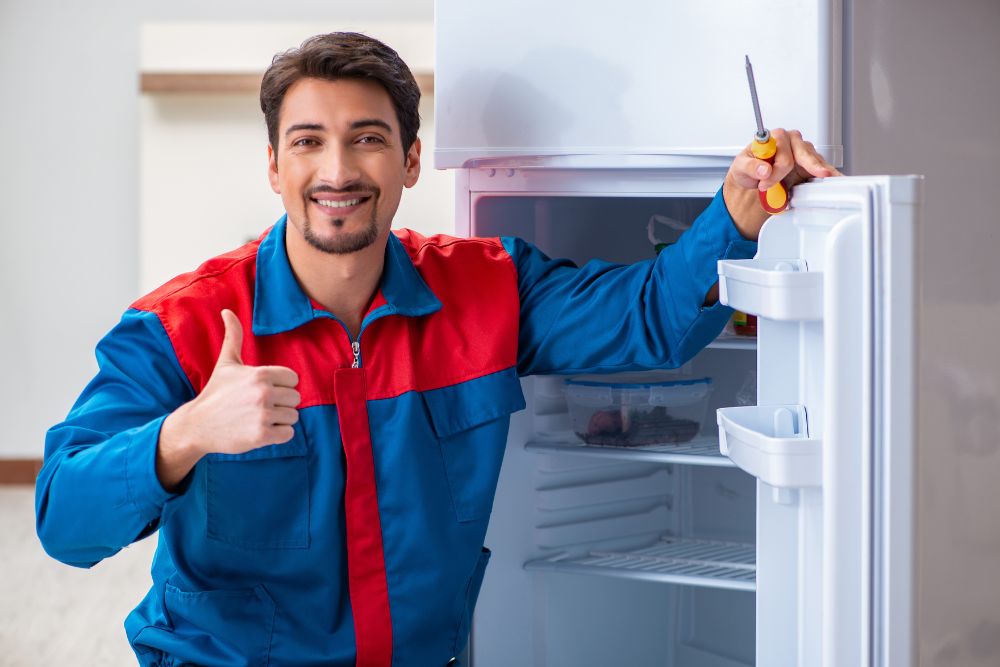 A man in a blue jacket and red shirt stands by an open refrigerator, showcasing commercial appliance repair services in Washington, DC.
